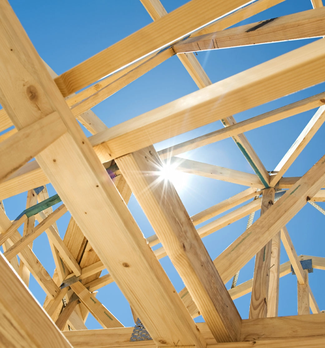 New residential construction home framing against a blue sky and sun